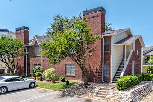 A house with a red brick exterior and a white car parked in front.