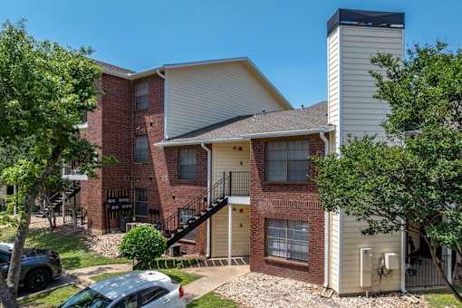 A two-story apartment building with a brick facade and a white exterior.