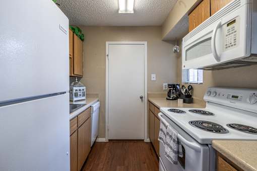 A white refrigerator is in a kitchen with a white door and a white stove.