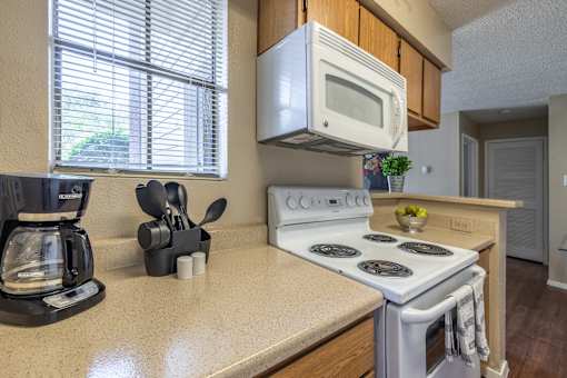 A kitchen with a white stove top oven and a white microwave above it.