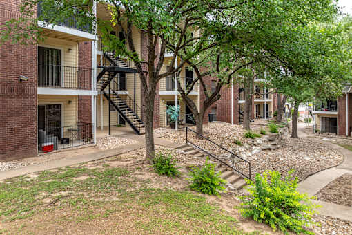 A tree in front of a brick building with a staircase.