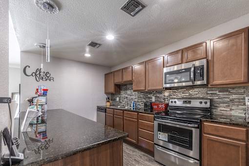 A kitchen with a granite countertop and wooden cabinets.