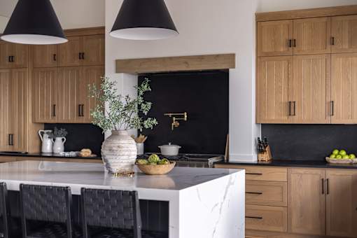 A kitchen with wooden cabinets and black pendant lights.