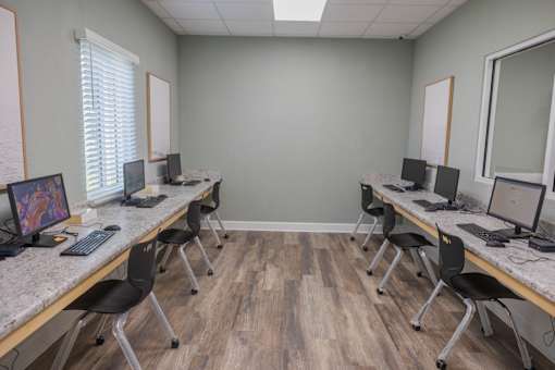 A room with a desk and chairs with a computer on it.