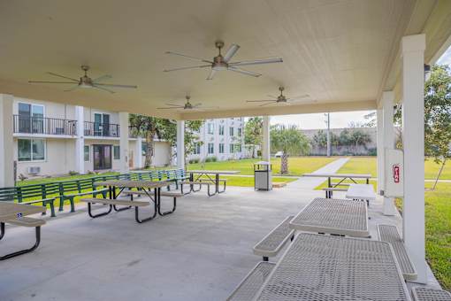 A covered patio with benches and ceiling fans.