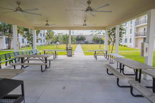 A covered patio with tables and chairs and ceiling fans.