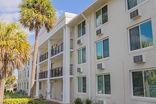 A white apartment building with balconies and air conditioning units.