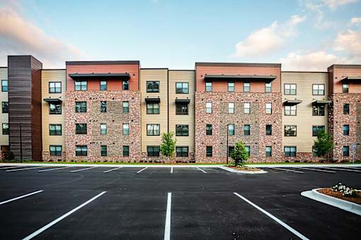 A large parking lot in front of a multi-story brick building.