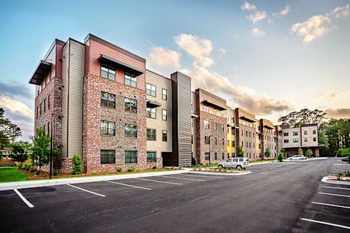 A large apartment complex with a parking lot in front.