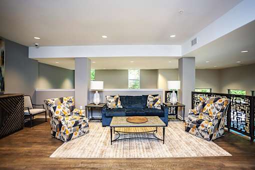 A living room with a blue couch and patterned chairs.