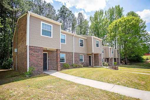 A row of townhouses with a sidewalk in front.