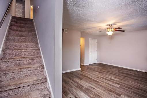 A room with a staircase and a ceiling fan.
