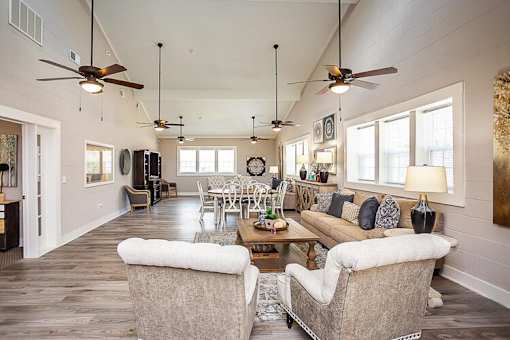 A living room with a couch, chairs, and a ceiling fan.