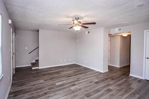 A room with a ceiling fan and wooden flooring.