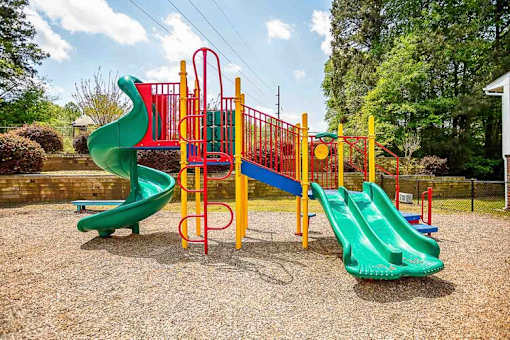 A playground with a green slide and a red and yellow structure.