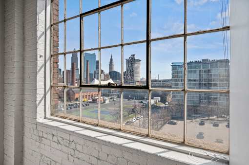 A view of a city skyline through a window with a brick wall on the left.