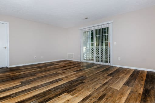 a bedroom with hardwood floors and a door to a balcony