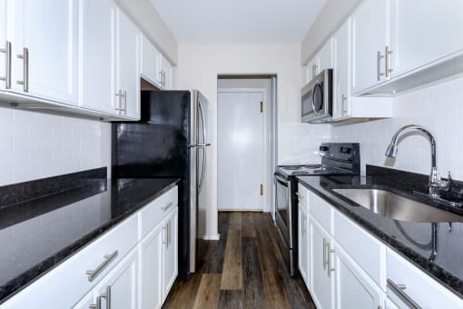 a kitchen with white cabinets and black countertops