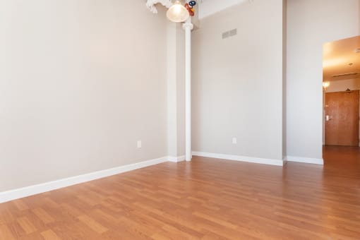 an empty living room with wood floors and white walls