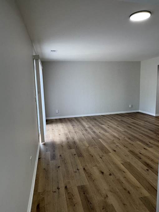 A room with wooden flooring and white walls.