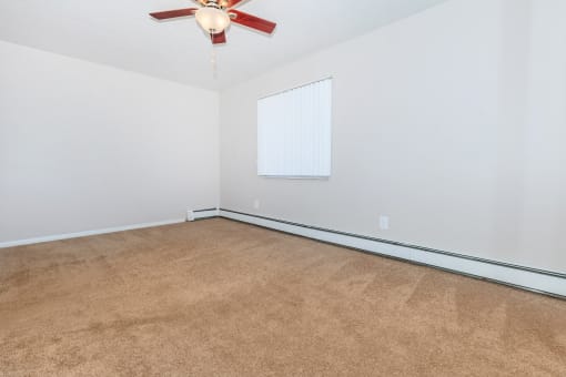 a bedroom with white walls and a ceiling fan