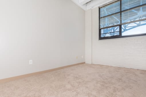 an empty living room with white walls and a window