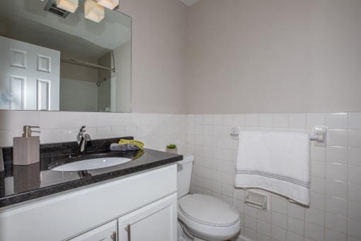 a bathroom with a white toilet next to a sink with a mirror above it