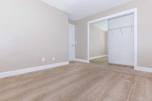 an empty bedroom with a closet and a mirror
