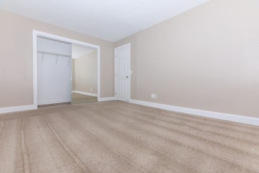 a bedroom with a door to a closet and a carpeted floor