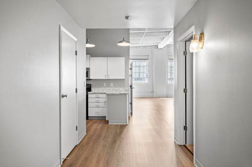 A kitchen with white cabinets and a wooden floor.