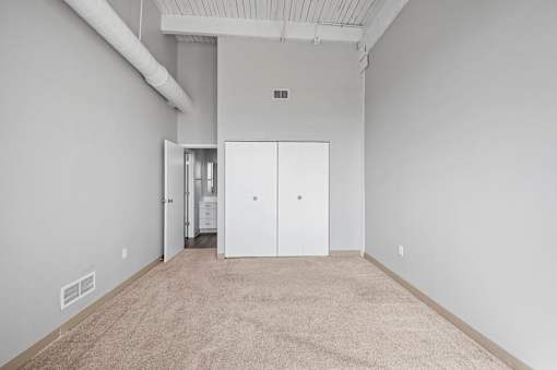 A room with white walls and carpeted floor with a white door in the middle.