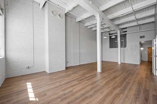 A spacious room with wooden floors and white walls.