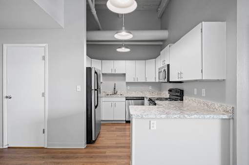 A kitchen with white cabinets and a marble countertop.