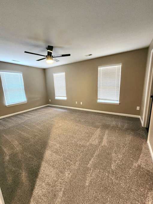 A room with a ceiling fan and carpeted floor.