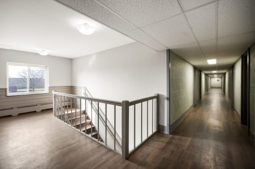the upstairs hallway of a building with stairs and a window