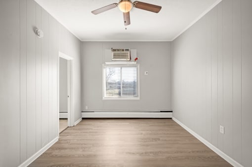 an empty room with a ceiling fan and a window