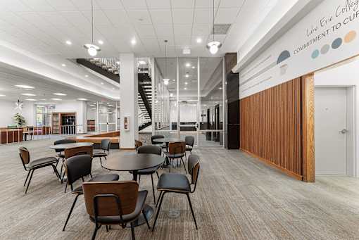 A modern interior of Lake Erie College with a staircase and a long table with chairs.