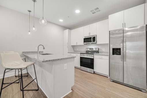 A modern kitchen with a white chair and stainless steel appliances. at Park Lamont Townhomes Apartments, Cleveland, Ohio