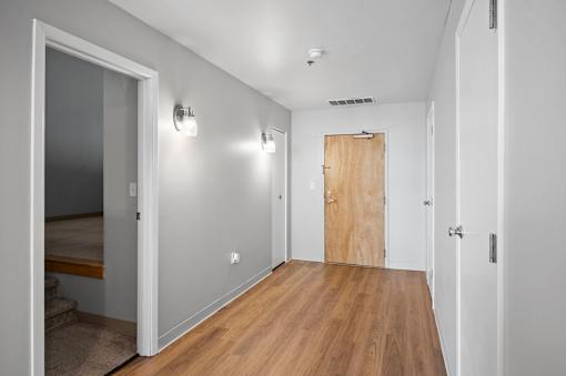 A hallway with a wooden floor and white walls.