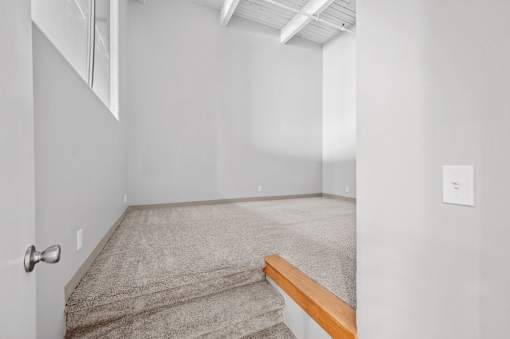 A room with a carpeted floor and a wooden bench.