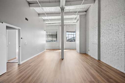 A long, empty room with white walls and wooden floors.