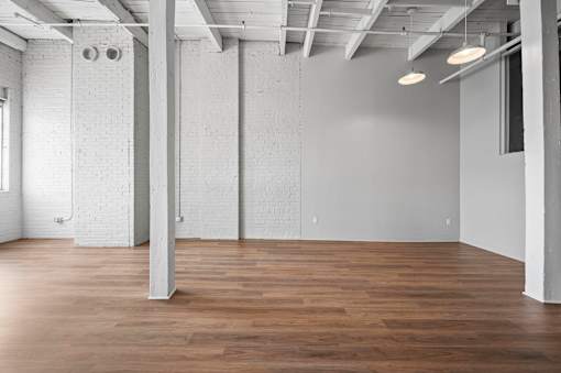 A large, empty room with wooden floors and white walls.