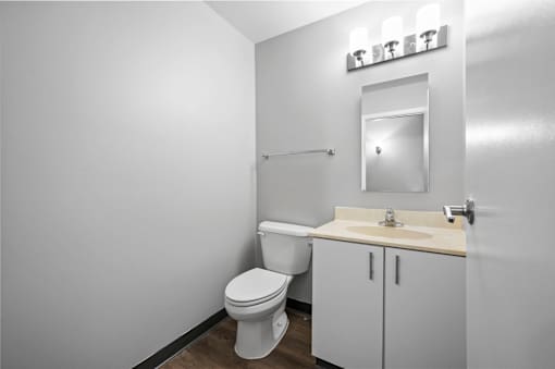 A white bathroom with a toilet, sink, and mirror.