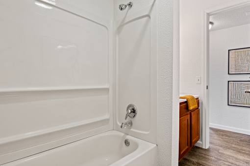 A white bathtub with a shower head and a wooden cabinet. at Vivo Toledo Apartments, Toledo, 43607