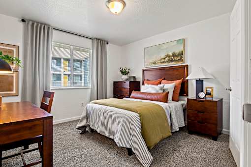 A bedroom with a bed, nightstand, and chair. at Vivo Toledo Apartments, Toledo, Ohio