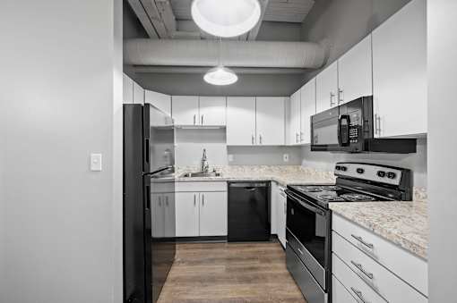 A modern kitchen with black and white appliances and cabinets.