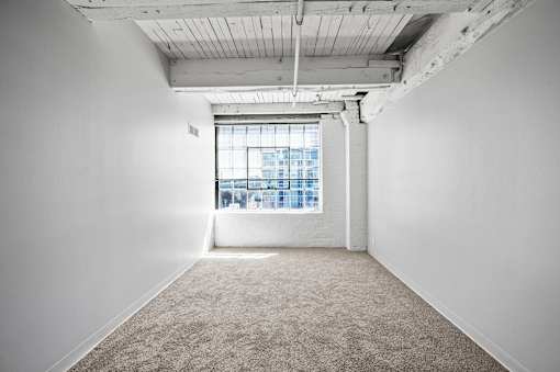 A large empty room with a window overlooking a cityscape.