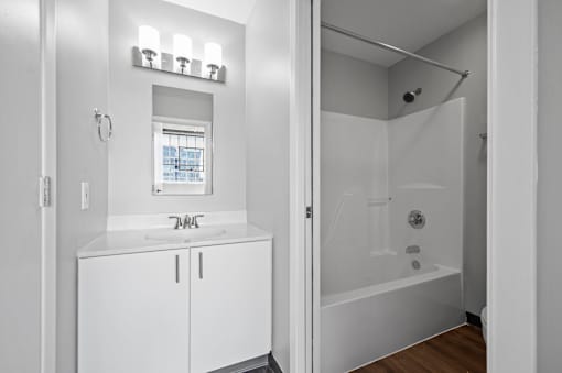A white bathroom with a glass shower stall and a window.