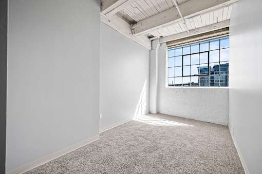 A large empty room with a window overlooking a cityscape.
