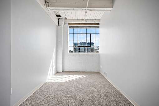 A large empty room with a window overlooking a cityscape.